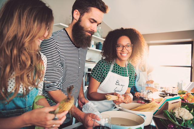 Vera Birkenbihl Online Sprachkurs Fortgeschrittene Kochen | Klarsicht-Verlag Drei Freunde internationaler Herkunft stehen zuhause in der Kueche und kochen gemeinsam.