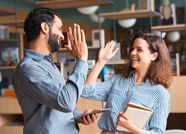 Vera Birkenbihl Online Sprachkurs Fortgeschrittene Team | Klarsicht-Verlag Ein Mann und eine Frau lachen sich zufrieden an und geben sich ein High Five mit den Haenden.